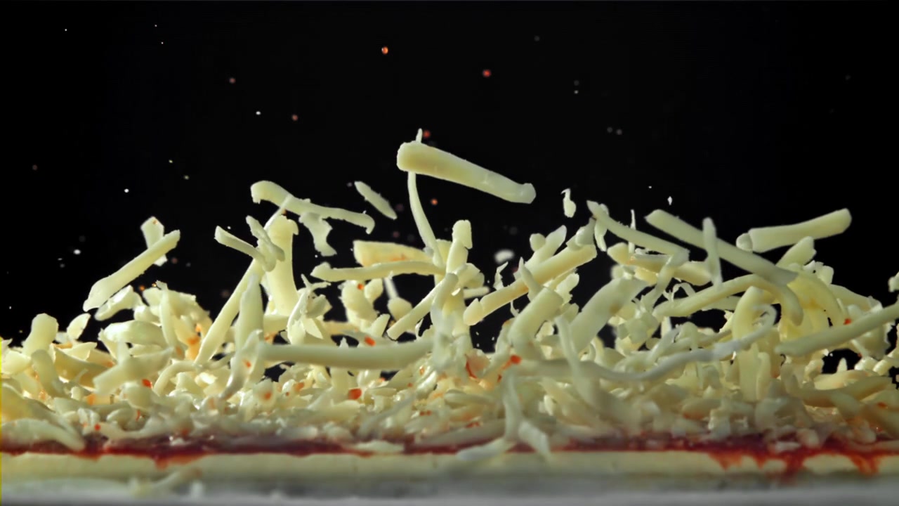 Shredded Mozzarella Cheese Sprinkling onto Raw Pizza Dough