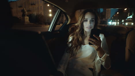 Business-lady-having-video-chat-on-smartphone-in-car.-Woman-working-overtime.