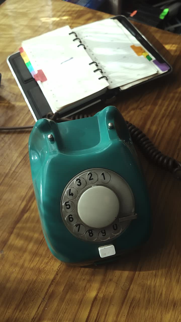 Person finger dials landline contact number on retro desktop telephone