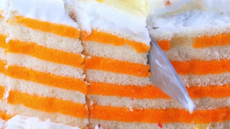 close-up view of a sliced layered orange cake with white frosting