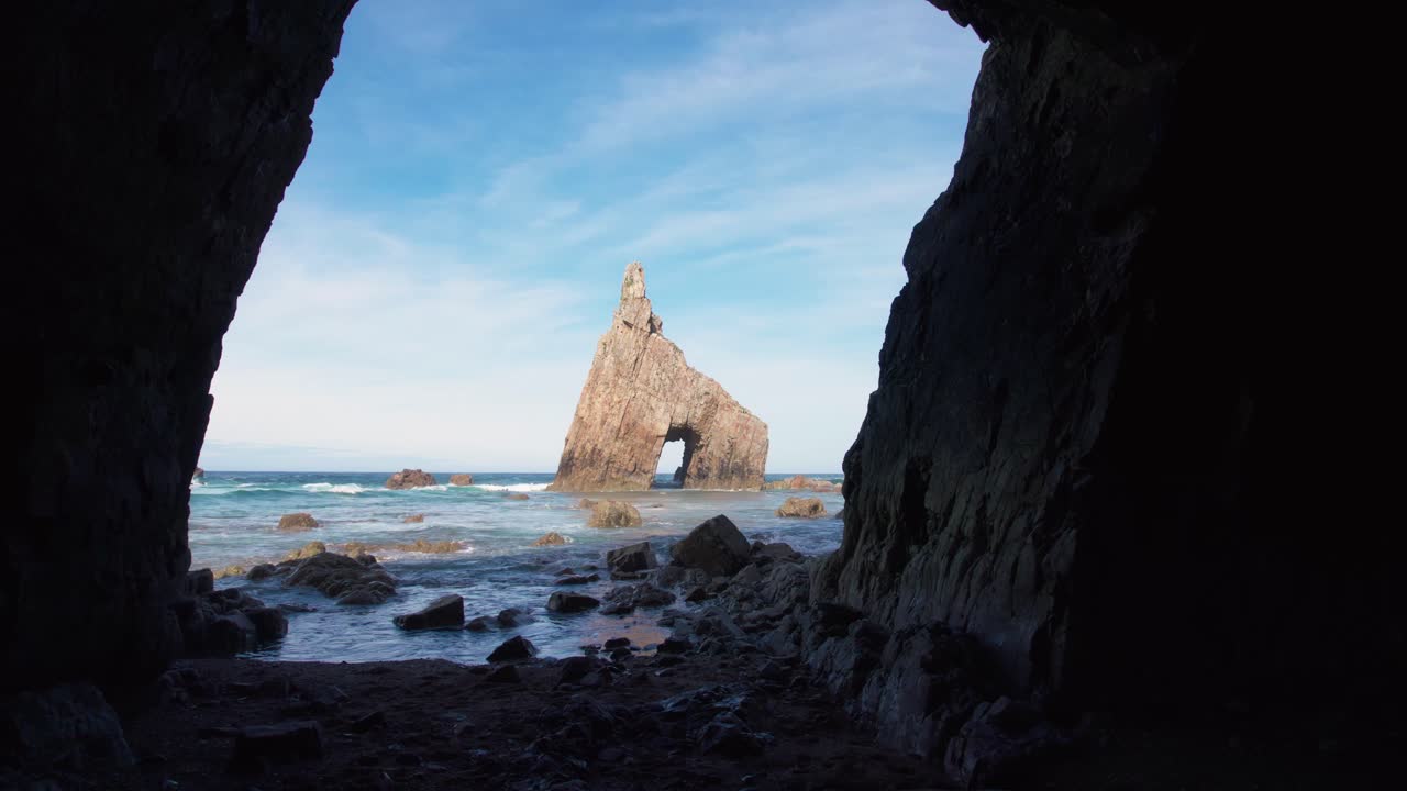 안정화 된 돌리 는 스페인 북부 의 배경 에 있는 바다 아치 와 함께 아스투리아스 의 캠피초스 해변 의 동굴 에서 앞으로 움직이고 있다