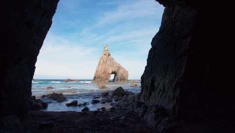 dolly estabilizado moviéndose hacia adelante fuera de la cueva en la playa de campiechos en asturias con el arco marino en el fondo en el norte de españa