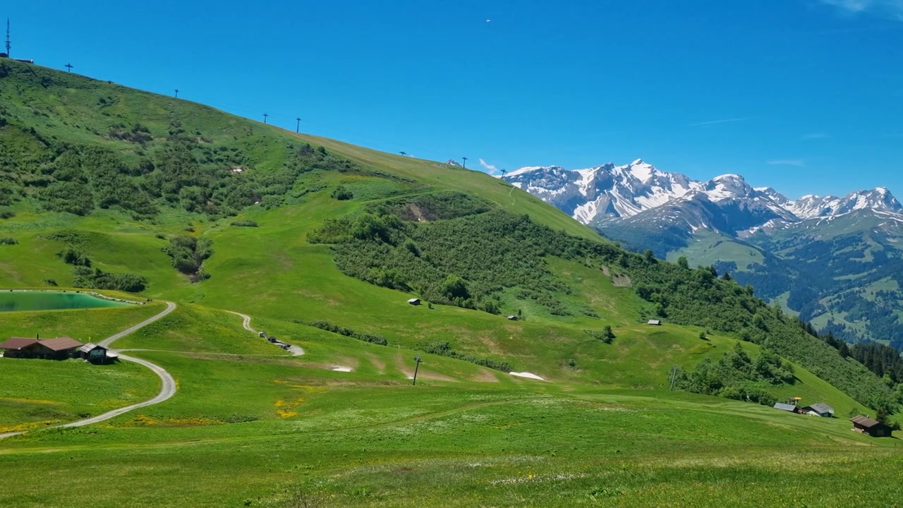Panoramautsikt fra Hahnenmoos i Berner Oberland, med utsikt over Metschstand og snødekte topper. Alpin sommereng, klar blå himmel, solfylt sveitsisk turparadis