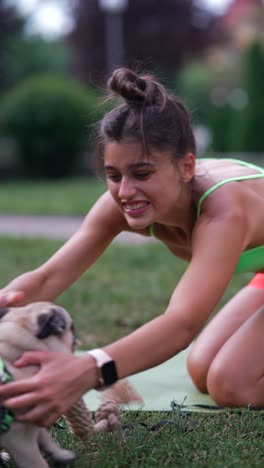 woman playing with her pug puppy in the park