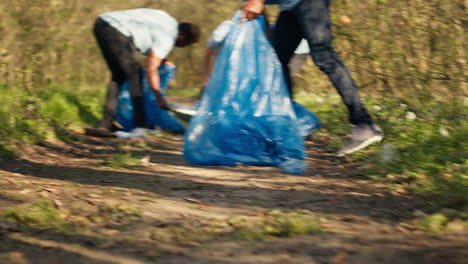 people picking up trash and plastic bottles from the forest area