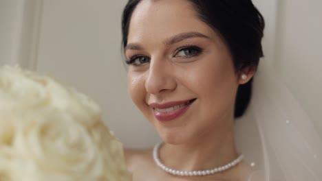 hermosa novia sonriendo a la cámara con un ramo de flores blancas