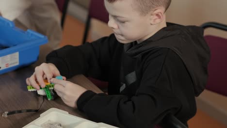 children intently focused on assembling parts from a robotics kit, with a tablet displaying instructions, promoting stem learning and creativity