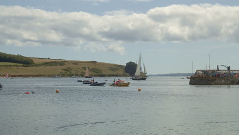 boats and swimmers pass near entry to st mawes port on sunny day