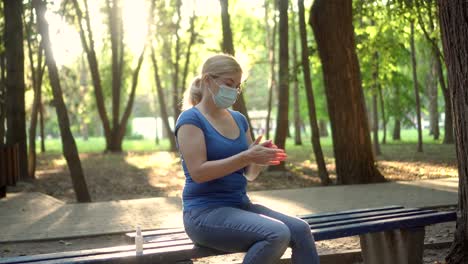 a woman in a medical mask treats her hands with antiseptic 01