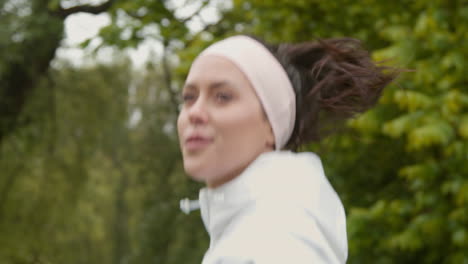 primer plano de una mujer con una cinta para la cabeza haciendo ejercicio manteniéndose en forma corriendo en el campo o en el parque 3