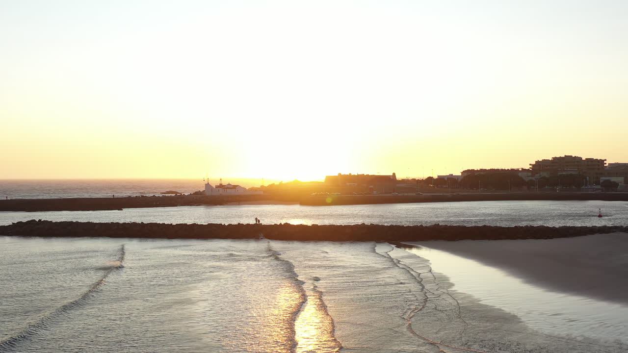 따뜻한 황금빛 해가 비어있는 해변에서 지평선을 깨뜨립니다.