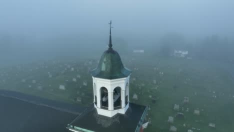 órbita aérea de la torre de la iglesia con un cementerio brumoso en el fondo