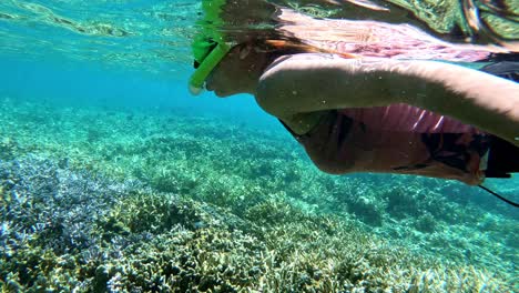 mujer asiática disfrutando del esnórquel sobre los corales pedregosos en el agua turquesa del mar de cebú, filipinas
