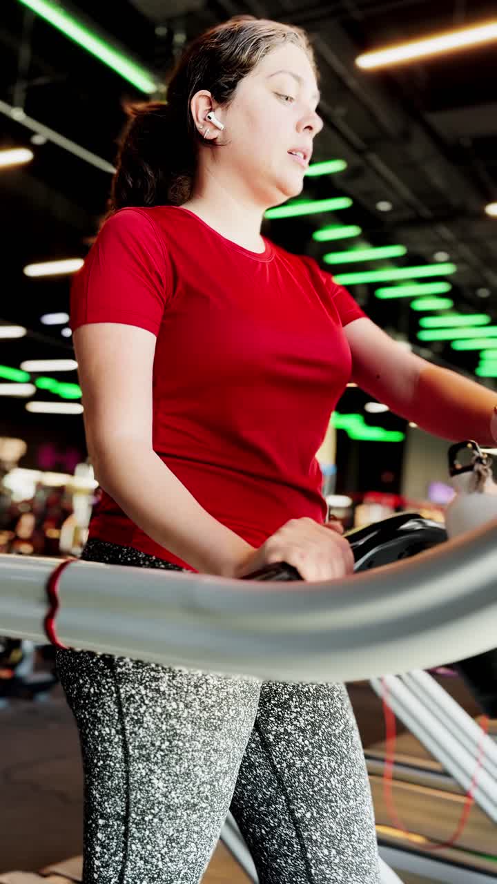 Young woman walking on treadmill at gym