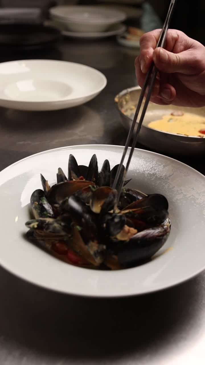 Chef Plating Fresh Mussels with Sauce in a Restaurant Kitchen