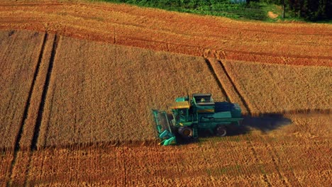 green combine harvester on a wheat field in lithuania - aerial shot