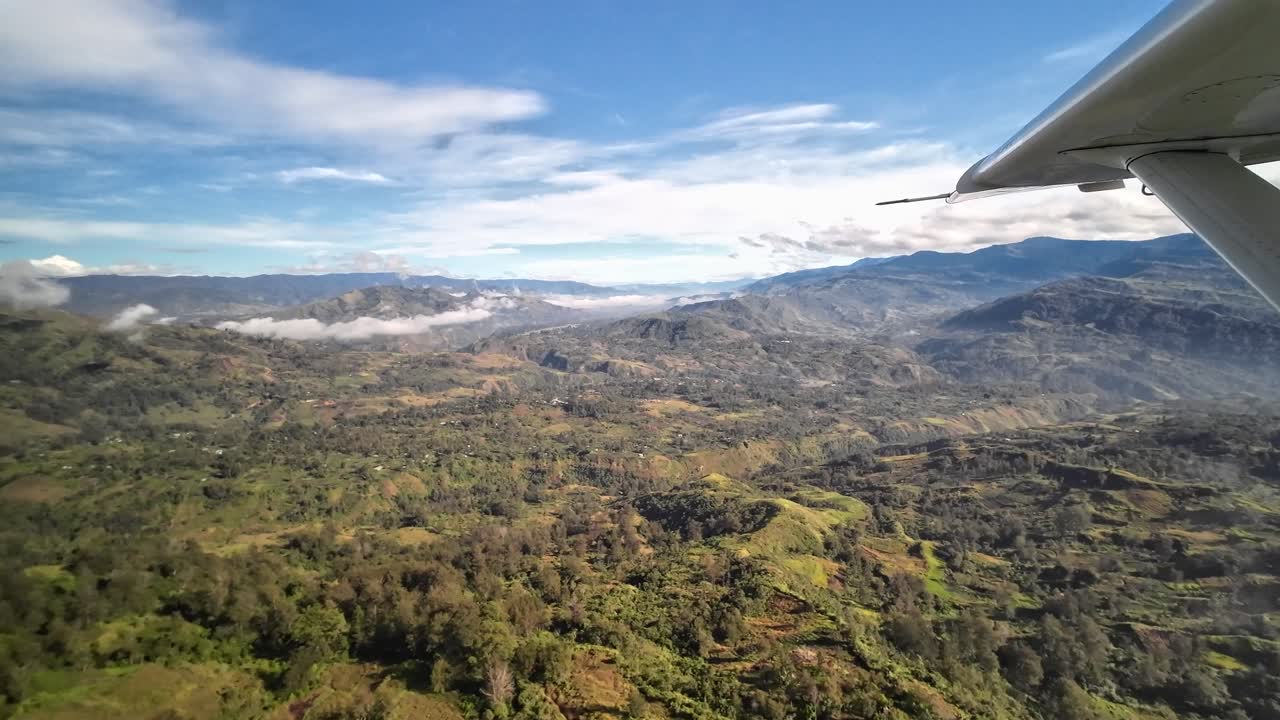 Flying over remote green mountain landscape in small airplane, Papua New Guinea