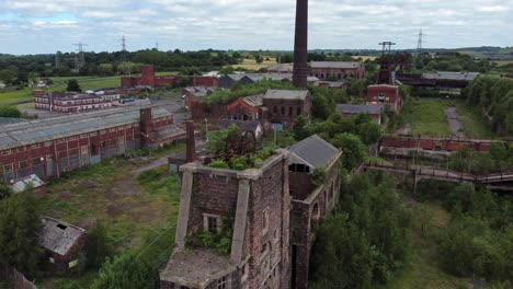 abandoned old overgrown coal mine industrial rusting pit wheel ruin aerial view descending pull back