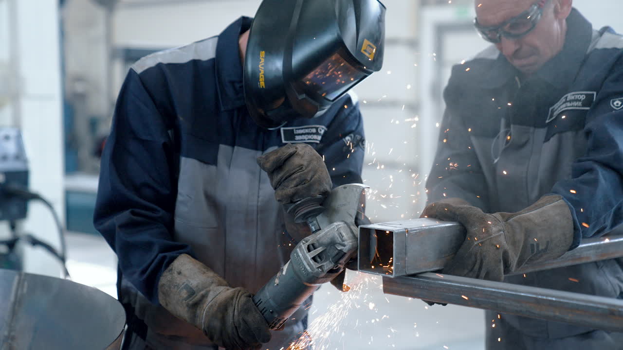 VINNYTSIA, UKRAINE - JANUARY 19, 2023: Two mans is cutting a metal by angle grinder saw. Bright sparks from cutting metal