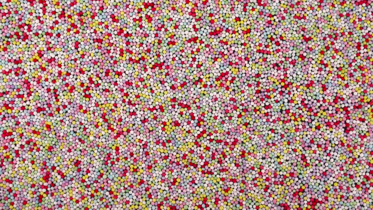 Top view from above of small colorful sprinkles sugar candies rotating. Background.
