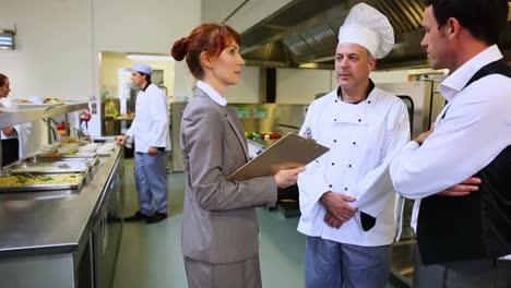 Restaurant-manager-chatting-with-waiter-and-head-chef
