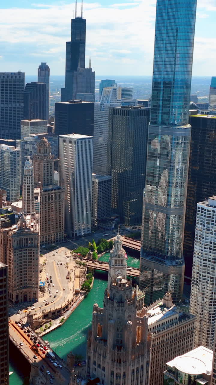 Downtown Chicago with skyscrapers, river and bridges. River transport, boats. The Chicago Tribune building. Aerial view. Vertical video