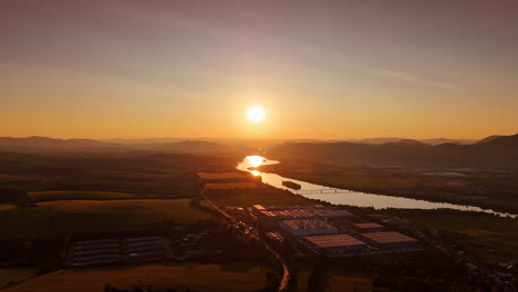 Sunset over river valley with mountains. Golden sunlight illuminates a tranquil river winding through a lush valley surrounded by distant mountains at dusk