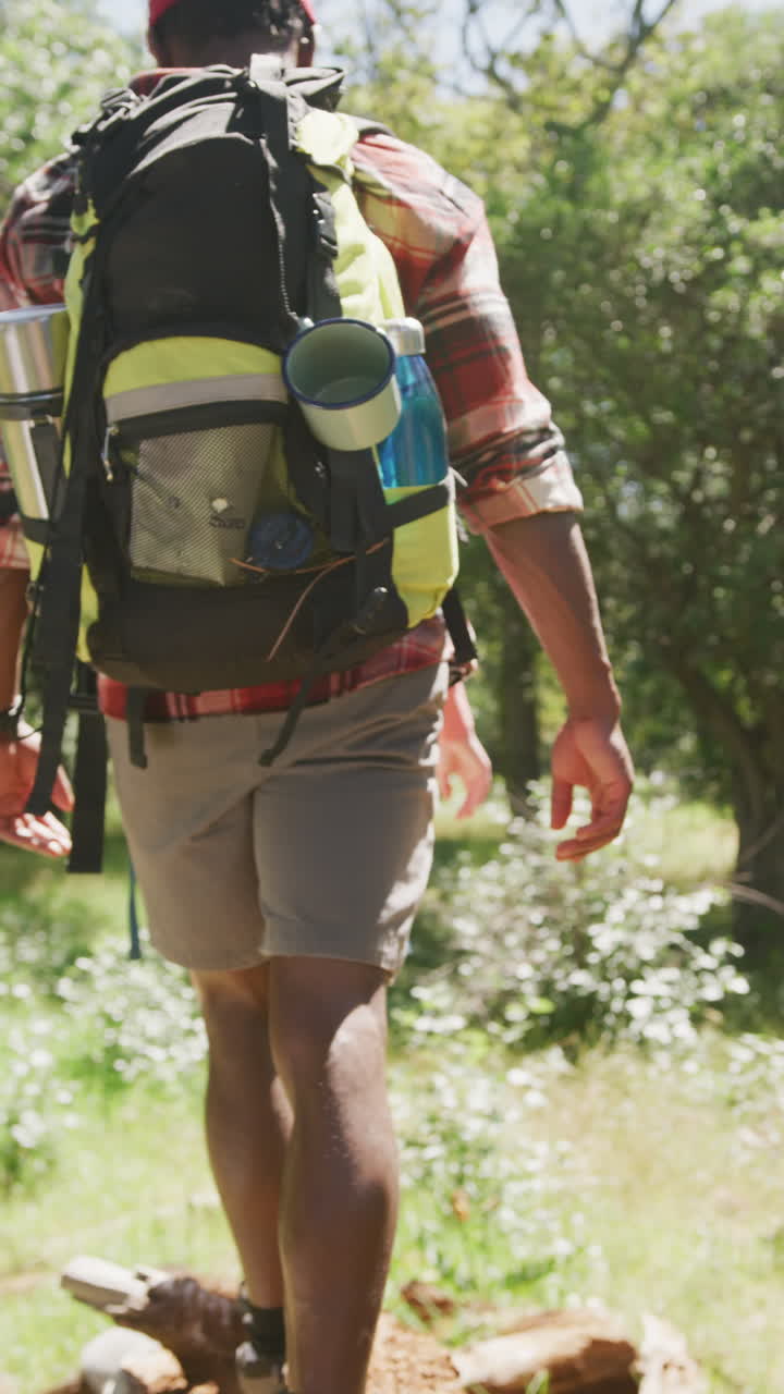 Vertical video of diverse couple hiking in park, slow motion