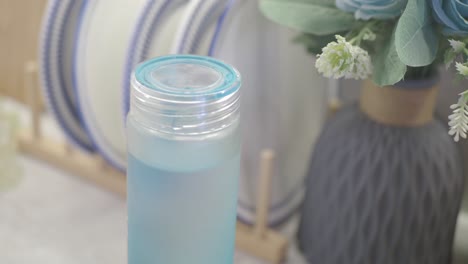 Water Bottle on Kitchen Counter with Dishes and Flowers