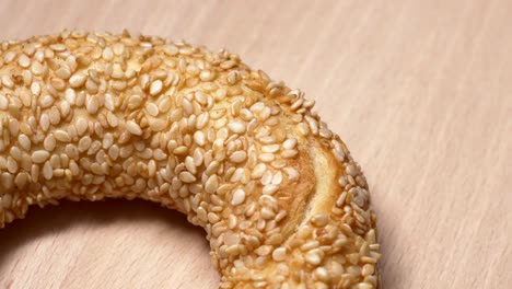 fresh bagels with sesame seeds in rotation. on wooden cutting board. extreme closeup.