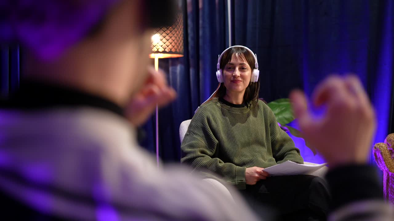 Donna sorridente con le cuffie seduta per un'intervista o un podcast