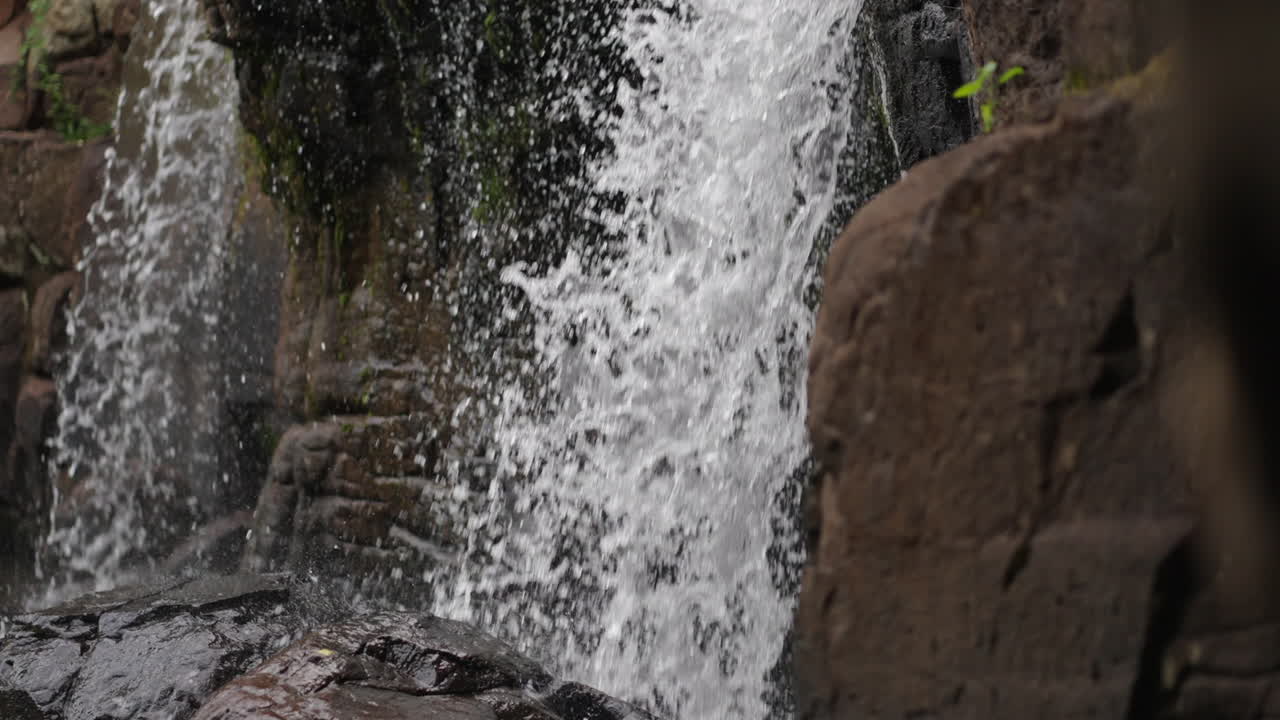 A serene ascend of Salto El Yerba waterfall in Misiones, water cascades on block rocks with dripping tendrils, natural beauty
