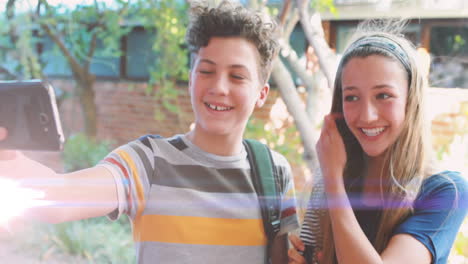 animación de luces sobre felices estudiantes adolescentes caucásicos masculinos y femeninos tomando selfies al aire libre