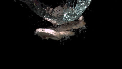 mushroom slices falling in water on black background