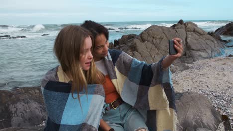 side view of a caucasian and a mixed race girl taking selfie seaside