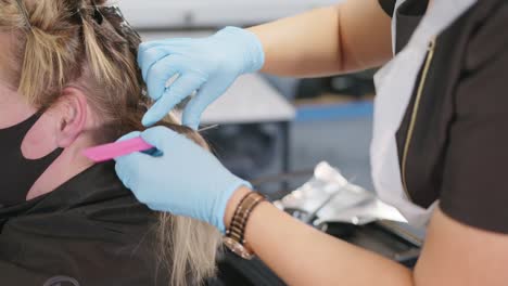 Slow-motion-shot-of-a-hairdresser-in-the-process-of-dyeing-a-customer's-hair-in-a-hair-salon