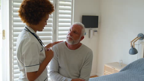 female nurse wearing uniform giving senior male patient bad news in private hospital room