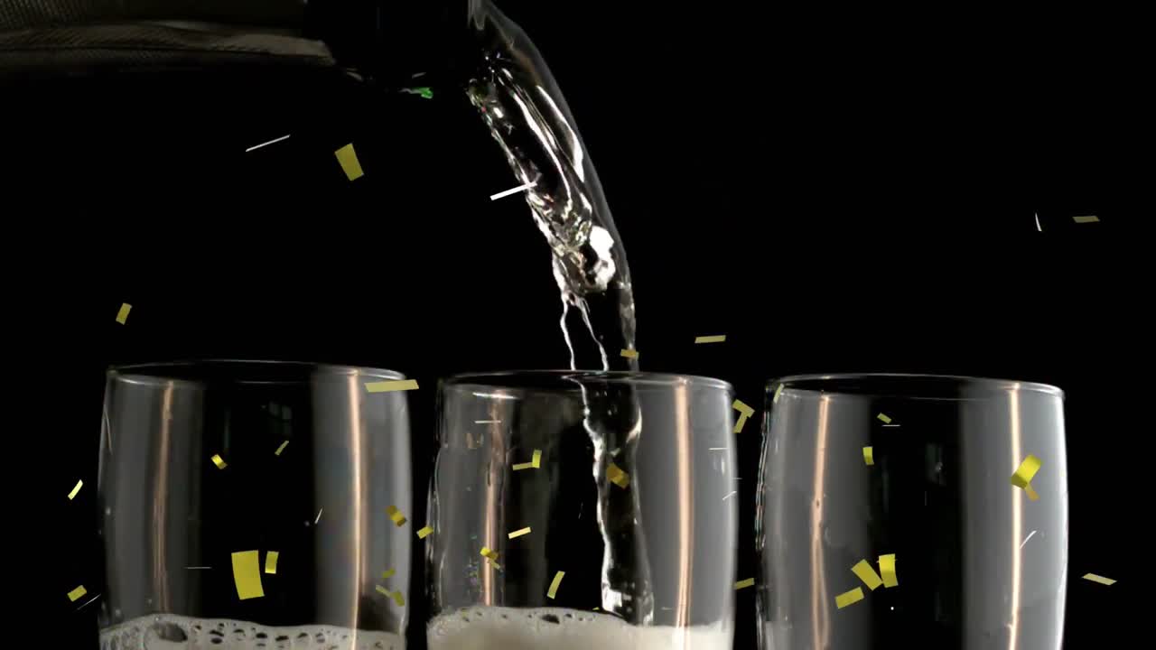Animation of gold confetti falling over champagne glasses on black background
