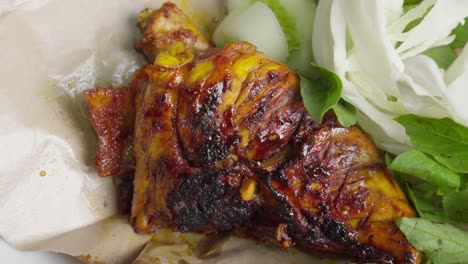 indonesian grilled chicken with perfect char on bed of cabbage and basil mint leaves, ayam bakar