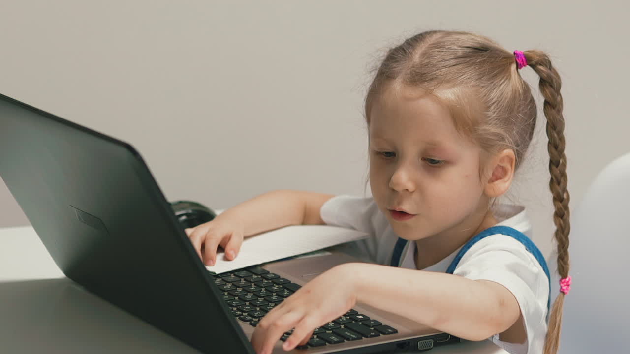 una niña en cámara lenta se sienta en la mesa con un cuaderno