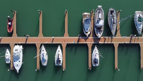 sailboats moored in port with green water on sunny day. top aerial view