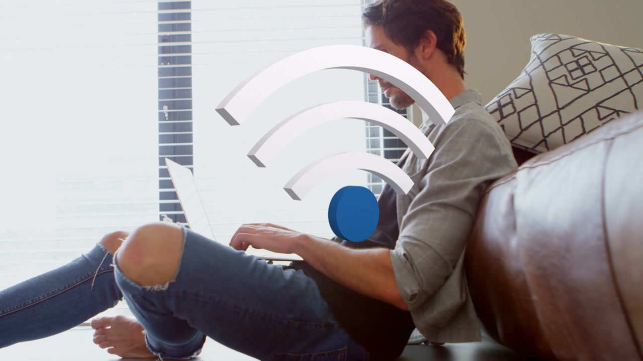 Man sitting on floor typing laptop, starting Wi-Fi graphic growing over lap, showing connectivity
