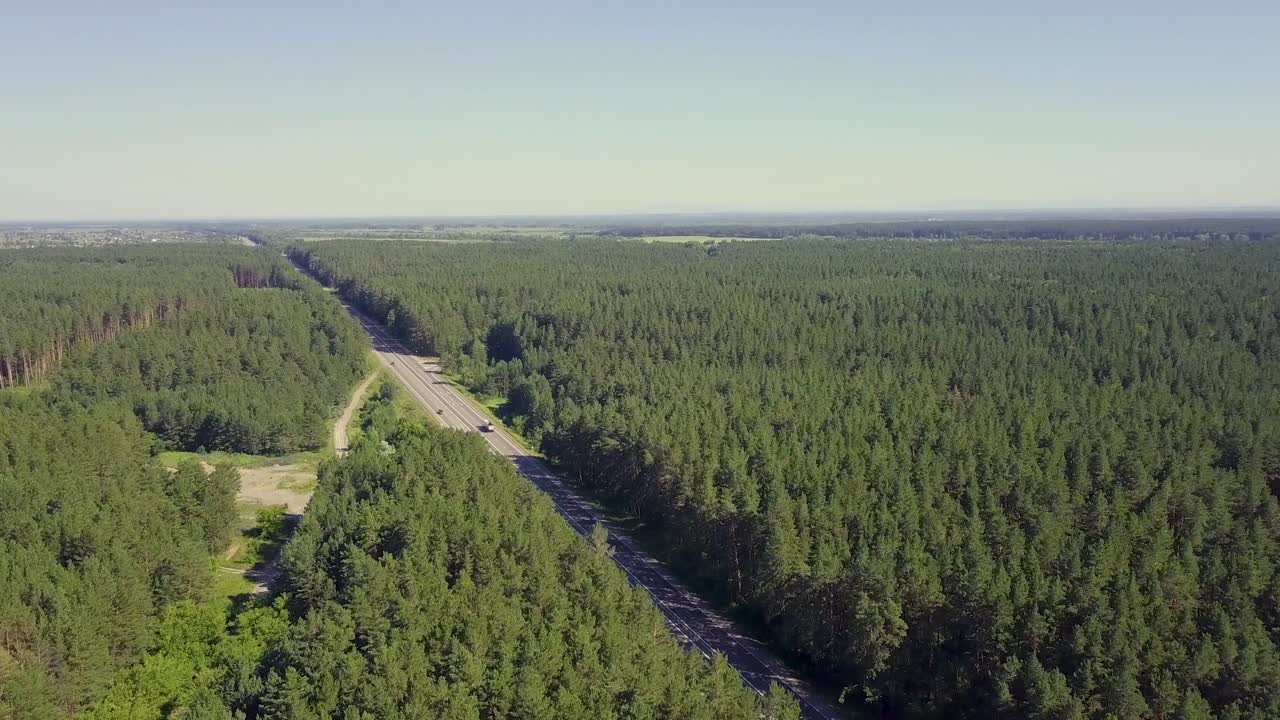 los coches aéreos se mueven a lo largo de la carretera a través del bosque de coníferas en la distancia se pueden ver los campos las aldeas