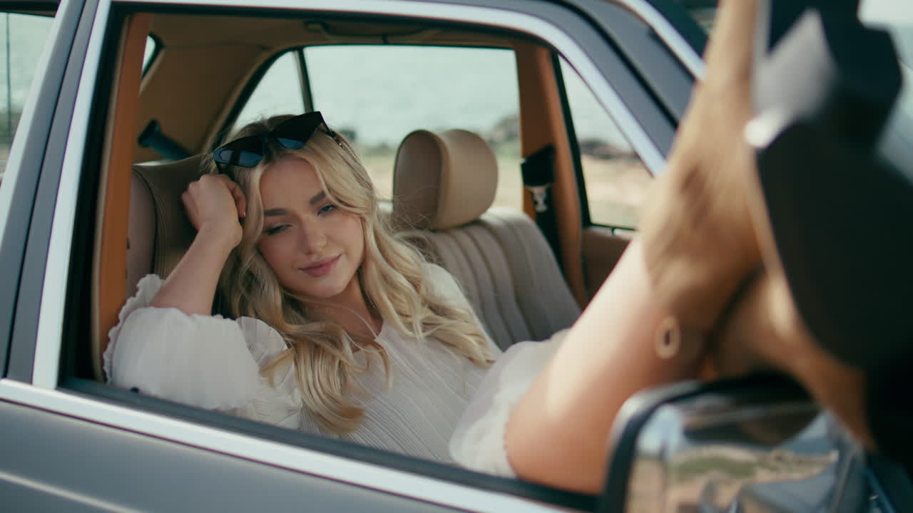 Gorgeous model posing automobile putting feet out open window closeup. Retro car