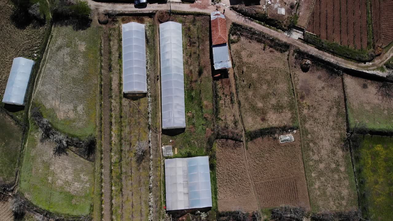 invernaderos en parcelas agrícolas cerca de casas de pueblo, vista de arriba hacia abajo