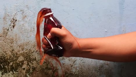 hand squeeze the bottle filled with red liquid until it spurts in slow motion