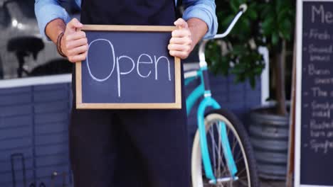 Waiter-showing-chalkboard-with-open-sign