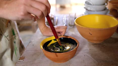 hands of female potter mixing paint into bowl