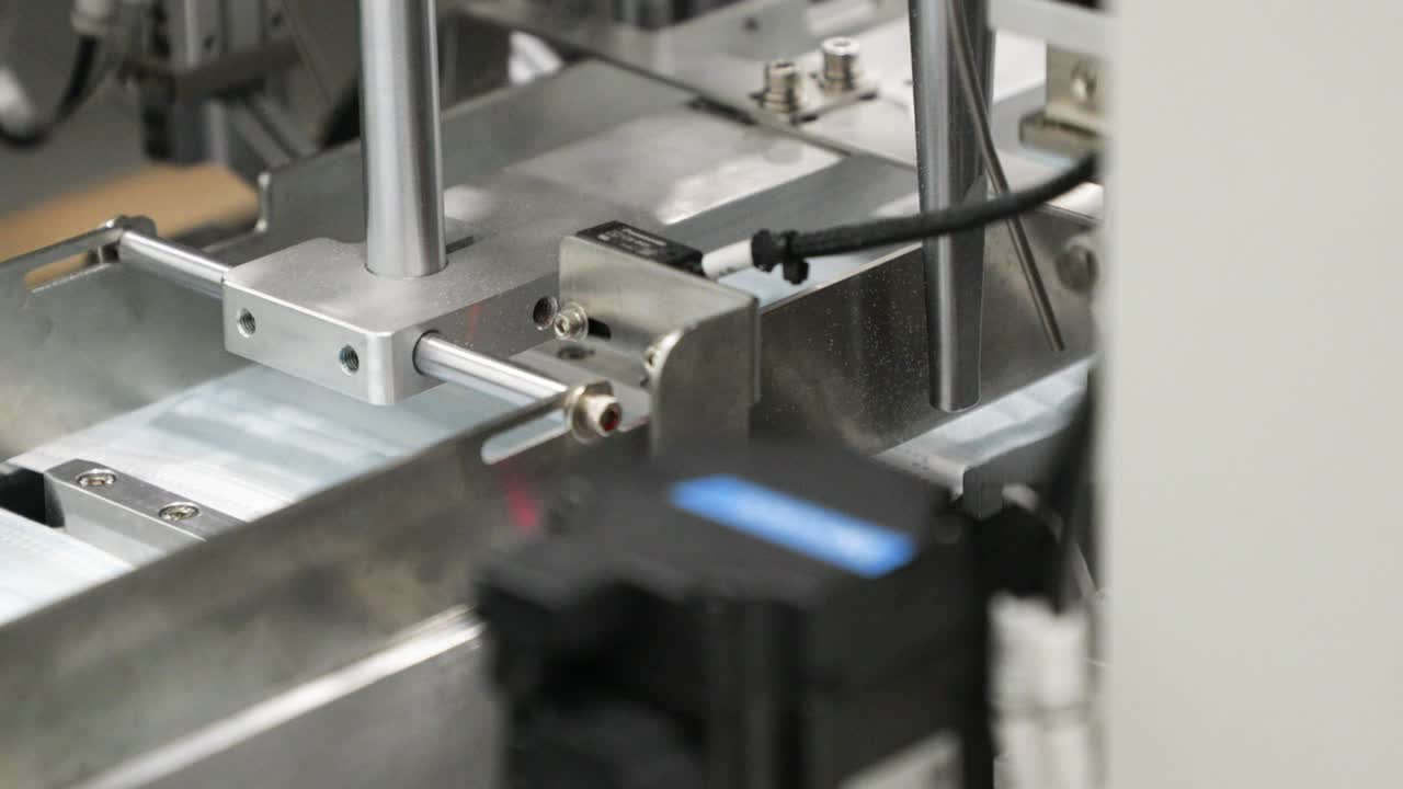 máquina de fijación de bucles auriculares a las telas plisadas de la máscara quirúrgica en el transportador. producción industrial de máscaras