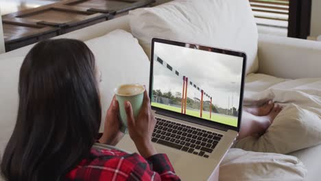 composite of woman sitting at home holding coffee watching athletics running event on laptop